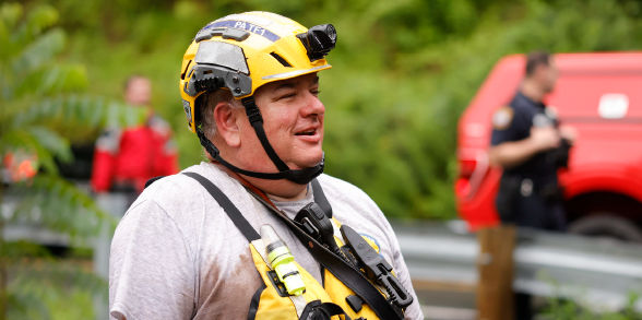 A PA Task Force 1 official responds to a disaster in a yellow helmet and vest.