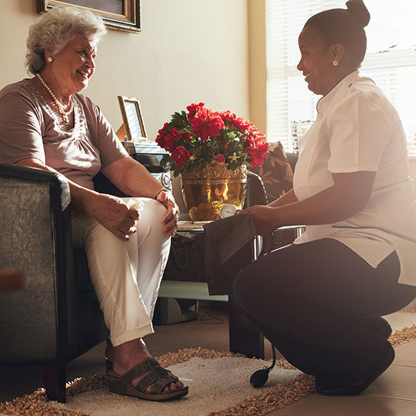 Nurse and elderly woman smiling at each other.