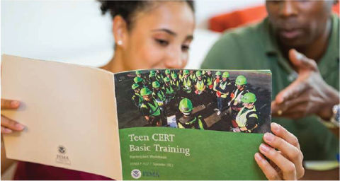 Two parents hold open a book from FEMA titled, "Teen CERT Basic Training."