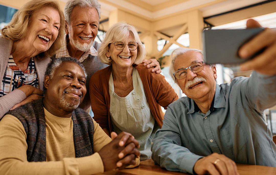 A group of senior citizens, taking a selfie in the library