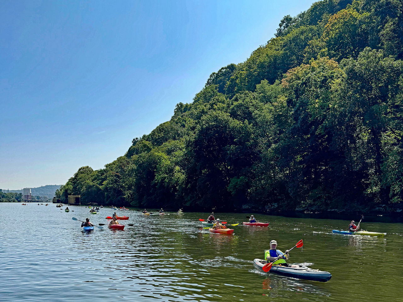 Group of sojourn paddlers on one of the Three Rivers with scenic forestry in the background