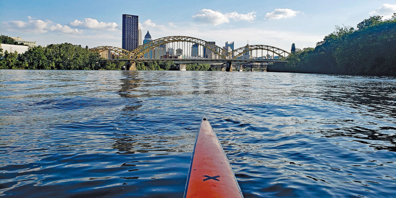 Tip of a long river kayak overlooking a beautiful, scenic view of the Pittsburgh skyline.