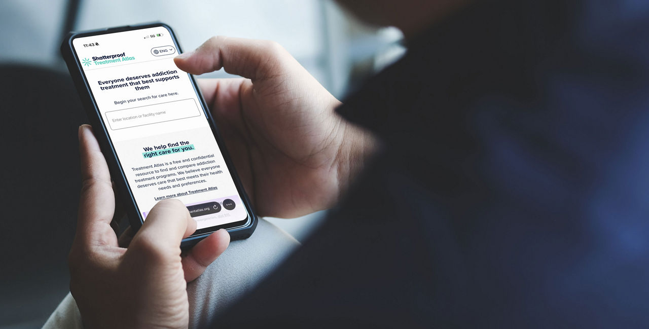 Person using a smartphone to view the Treatment Atlas website.