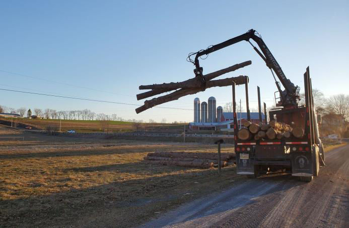 Photo of PFBC and partners using large machinery to carry logs to restore habitat to a stream in the Turtle Creek Watershed, PA