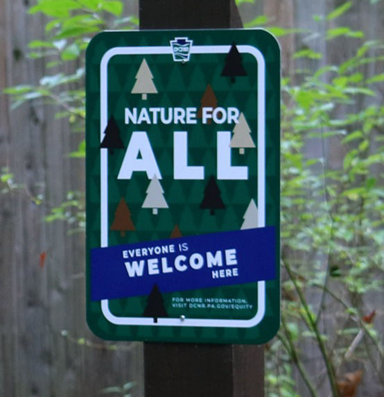 A green sign that reads Nature For All.