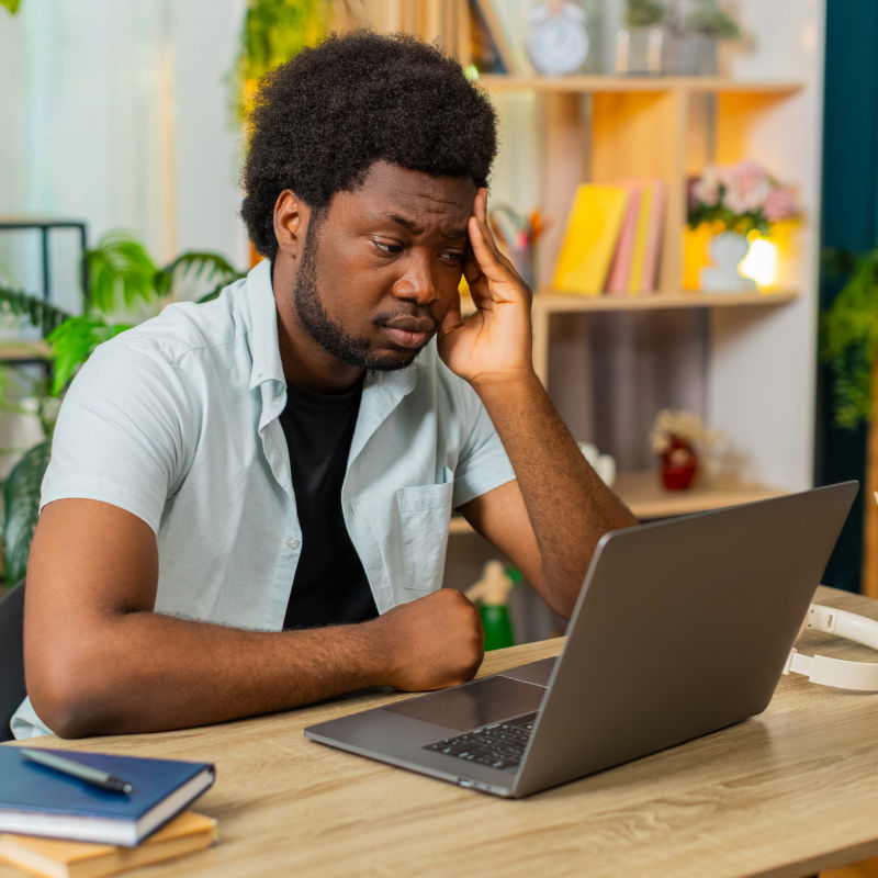 Man looking concerned while reviewing information on his laptop.