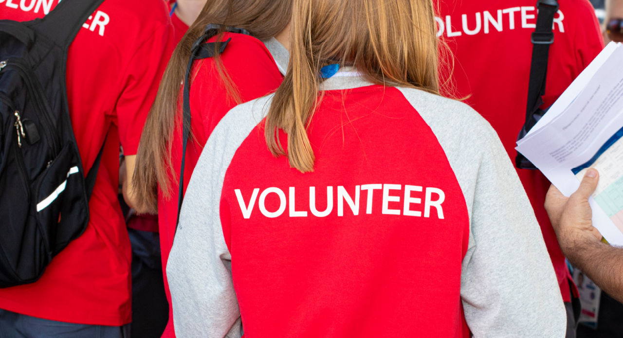 A group of people wear red 'Volunteer' vests.