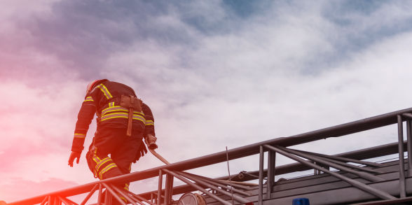 A firefighter climbs on a ladder atop a firetruck.