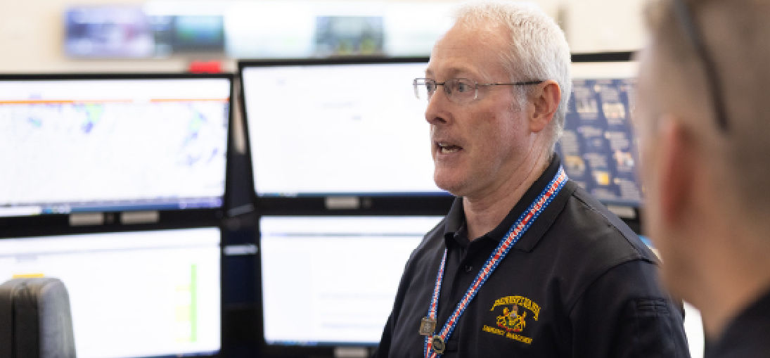 A watch officer stands in front of multiple screens his team monitors 24/7 for threats against Pennsylvania.