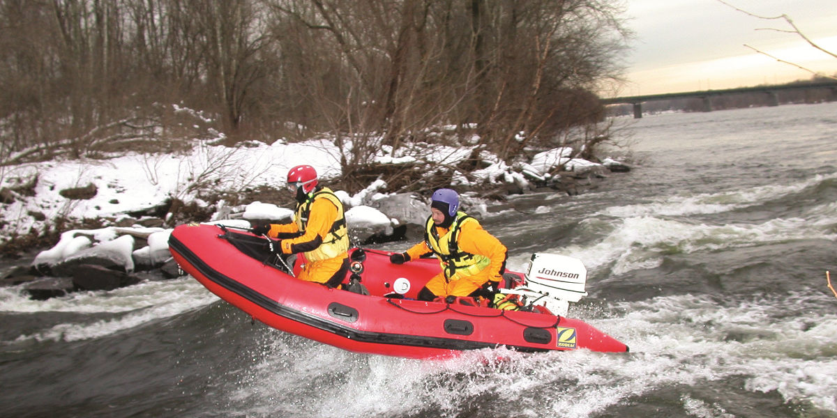 Two water rescuers in a rescue raft on a snowy day 