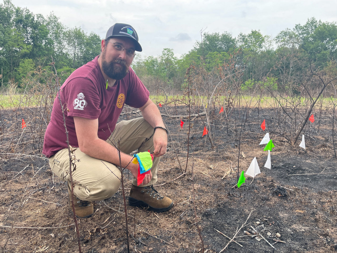 Assistant District Forester Jake Novitsky kneeling in a forested area.