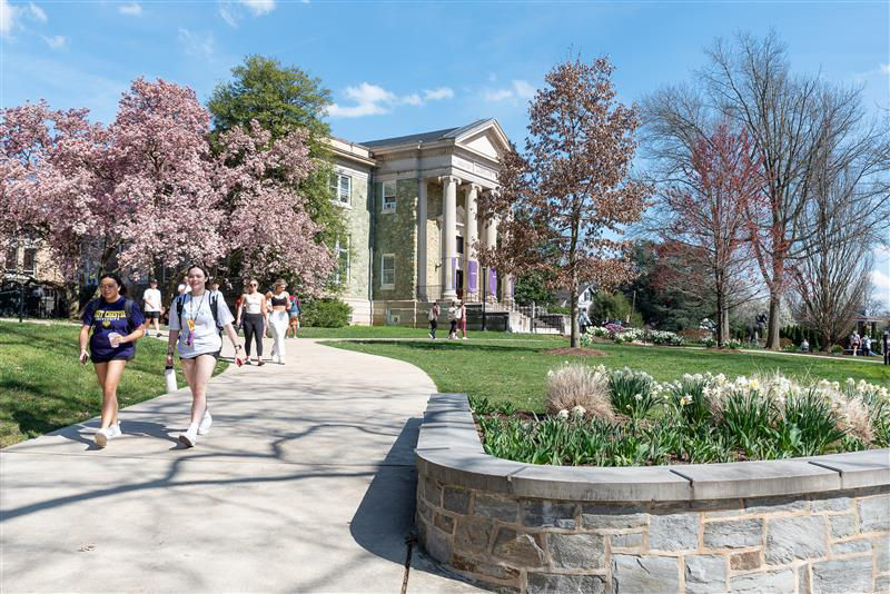 Exterior view of West Chester University's Pennsylvania's State System of Higher Education with students in the foreground.