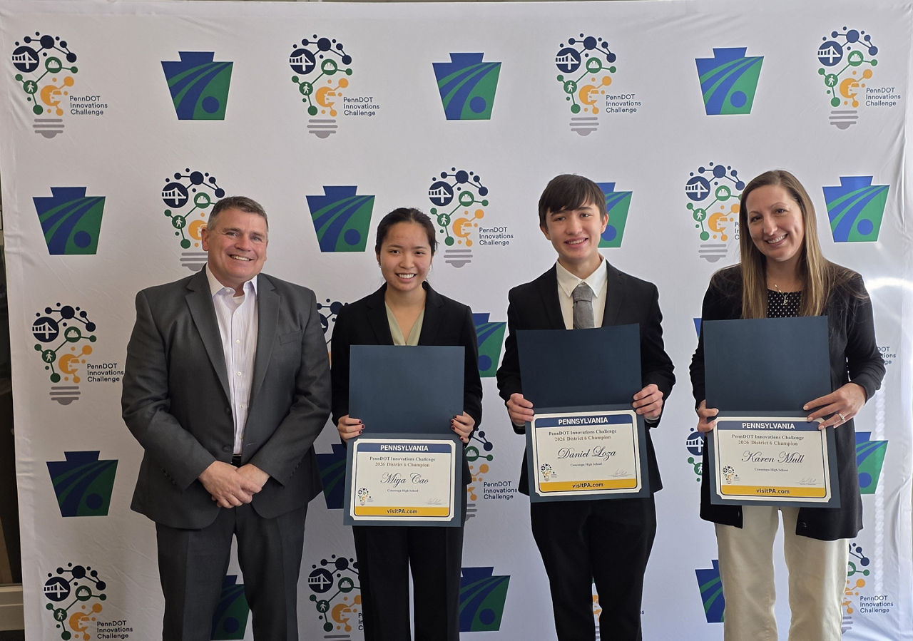 winning team members with certificates in front of challenge backdrop.
