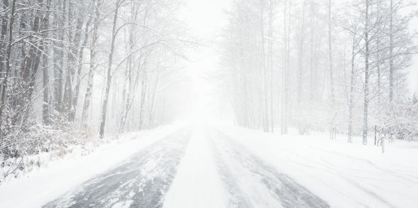 A snowy winter road in the woods.