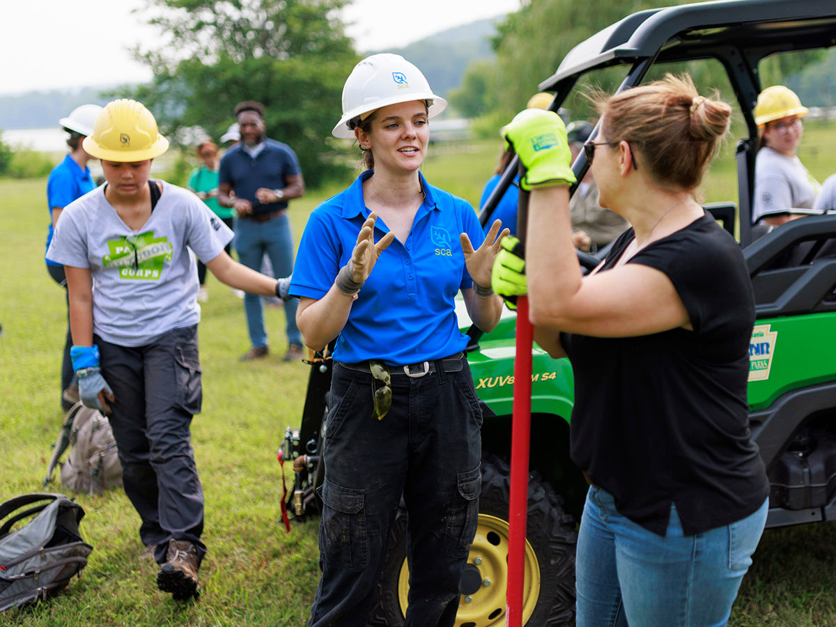 An Outdoor Corps Youth Leader speaks with First Lady Lori Shapiro in front of a motorized vehicle.