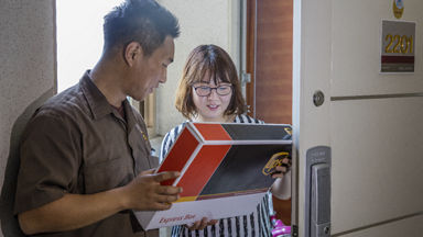 Driver delivering UPS Next Day Air package to woman