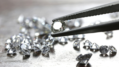Image of loose diamonds and one held by tweezer