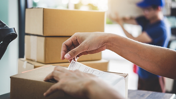 Close up of hands placing a label on a package 