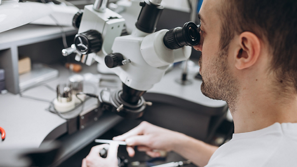 Male looking through a large magnifying machine 