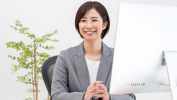 Female sitting at a desk with a computer and her hands folded together 