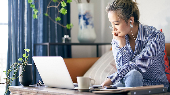 Female looking at her laptop and sitting on a couch 