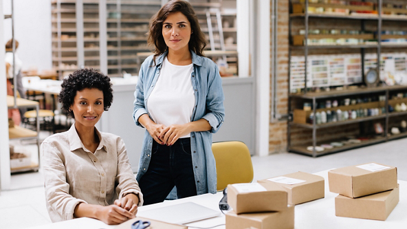 Female sitting at a table while another female stands behind her in a shop