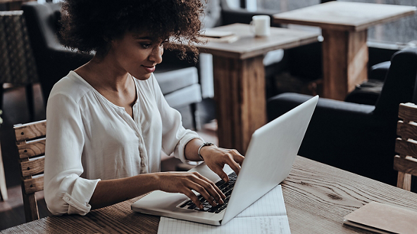 Female sitting at a café table using her laptop 