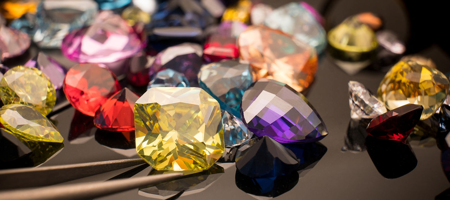Multiple gemstones in various shapes and colors on black background