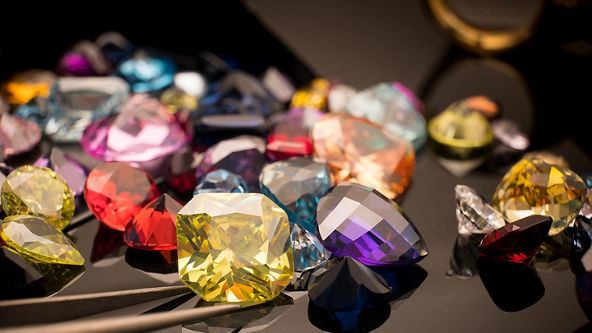 Multiple different colored gemstones on a shiny black background