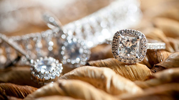 Diamond ring, earrings, and necklace on a woven background