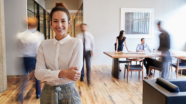 Female standing with arms folded in a busy office