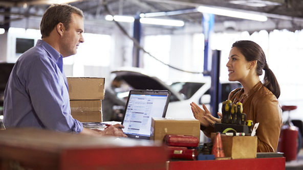 Woman talking with a man in a car repair shop