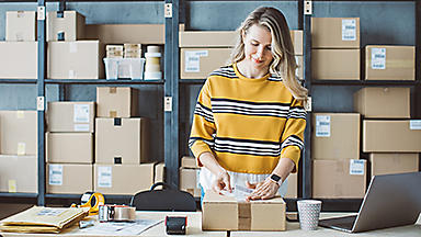 Woman putting a label on a box in warehouse