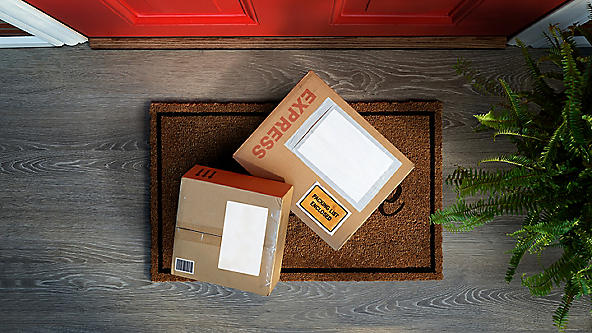 Two packages sitting on a welcome mat in front of a door 