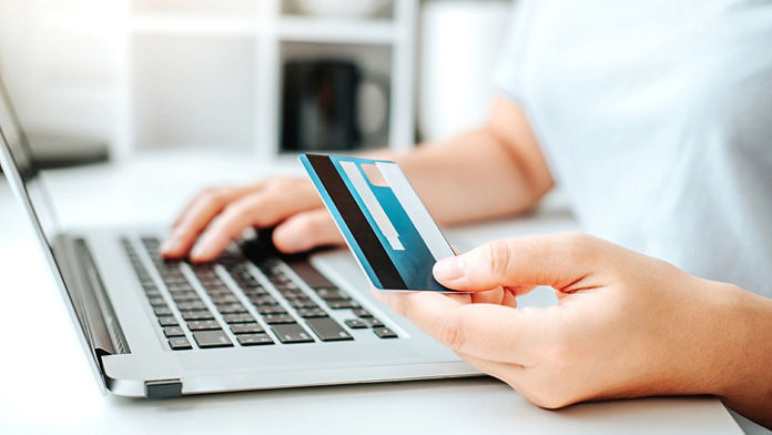 Close up of a woman's hands holding a credit card and entering information on laptop keyboard