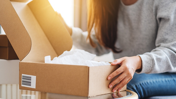 Close up of a female opening a box full of white tissue paper