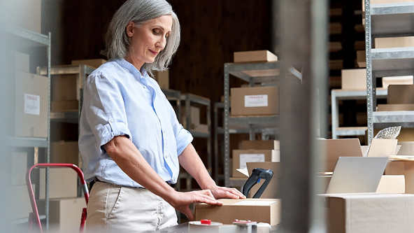 Female with her hands on a closed box in a store room full of boxes