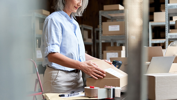 Female closing a box in a store room full of boxes