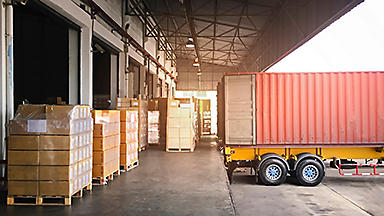 Semi-truck at a loading dock with pallets of boxes