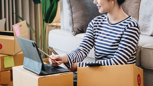Female using her tablet and sitting on the floor surrounded by boxes