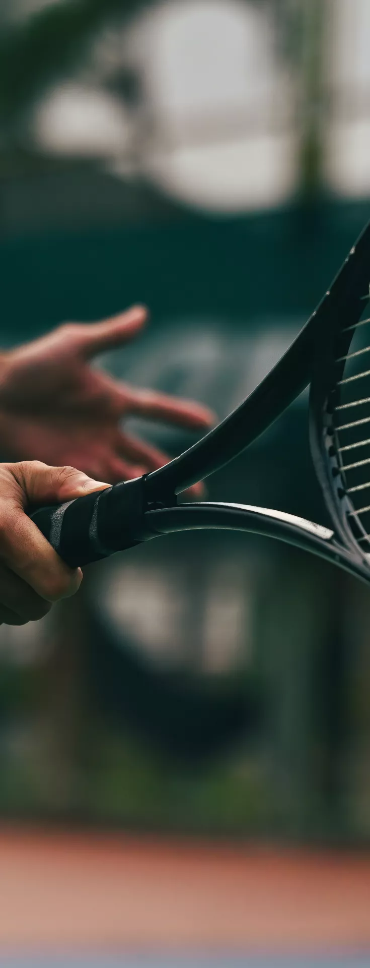 A tennis player swings the racket toward a fast-moving ball, captured in a dynamic close-up action shot on the court.