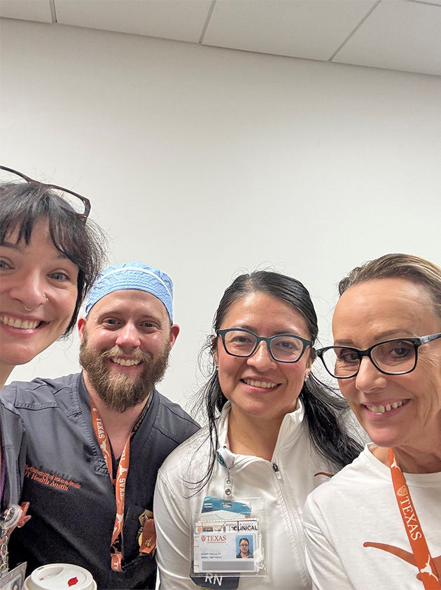 A group of medical professionals is pictured indoors, wearing uniforms and ID badges. The setting appears to be a hospital or clinical environment, with white walls and a ceiling visible in the background. Lanyards and badges display text such as 'RN' and 'TEXAS,' indicating roles and affiliations. The overall mood is professional and collaborative, with a neutral color palette dominated by white and orange accents.