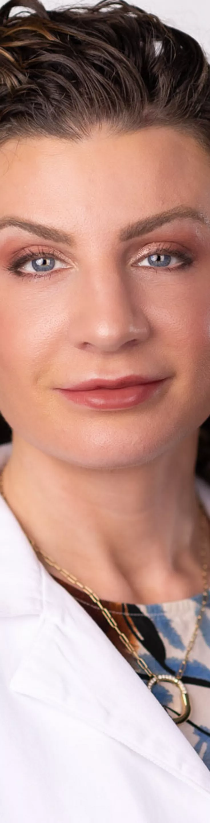 Headshot of Alisa Coker. She is wearing a multicolored blouse and a white coat.