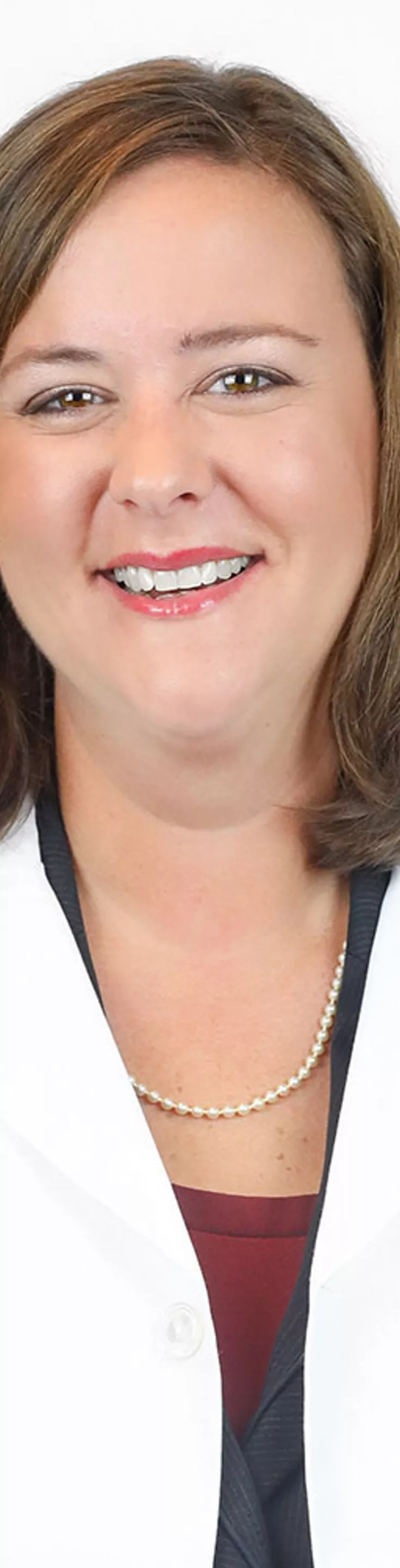 Headshot of Amanda White. She is wearing a white coat and a red shirt with a gray cardigan.