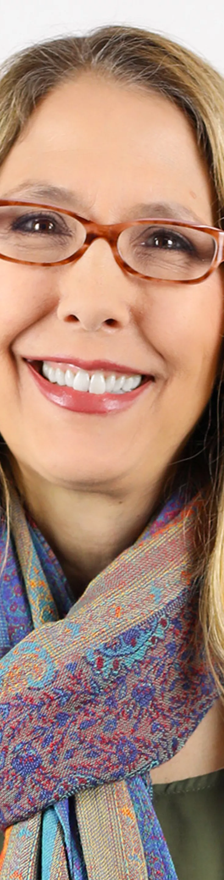 Headshot of Audrey Baum. She is wearing an olive green blouse, a multicolored scarf, and a white coat.