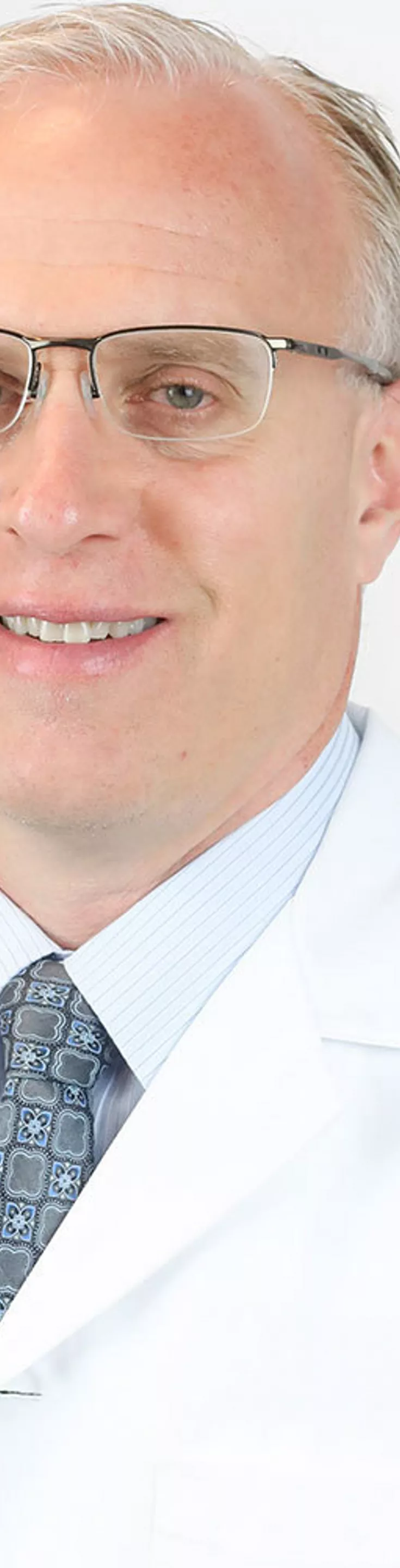 Headshot of Kevin Bozic. He is wearing a blue dress shirt, blue tie, and a white coat.