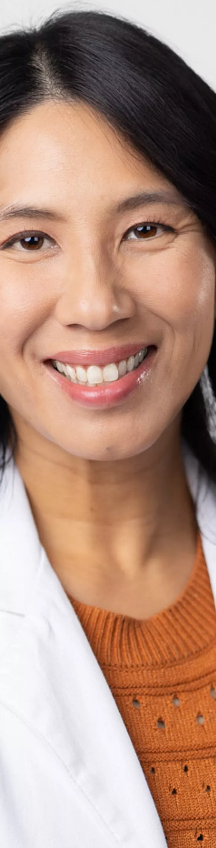 Headshot of Brenda Chang. She is wearing an orange sweater and a white coat.