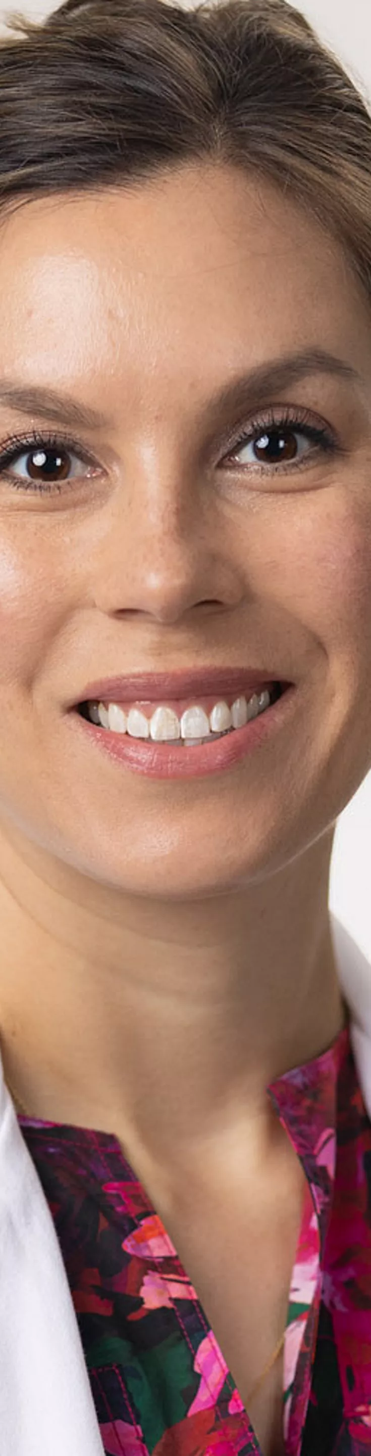 Headshot of Brittany Rosales. She is wearing a multicolored floral blouse and a white coat.