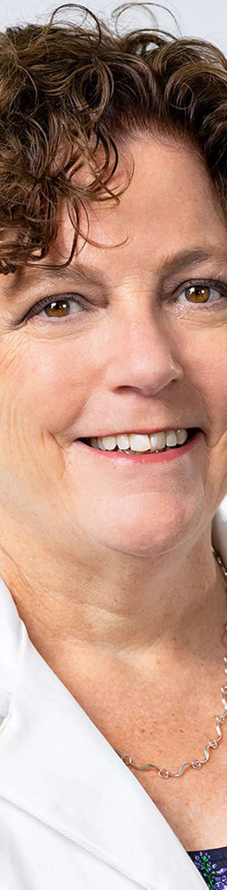 Headshot of Carol Alter. She is wearing a blue blouse and a white coat.