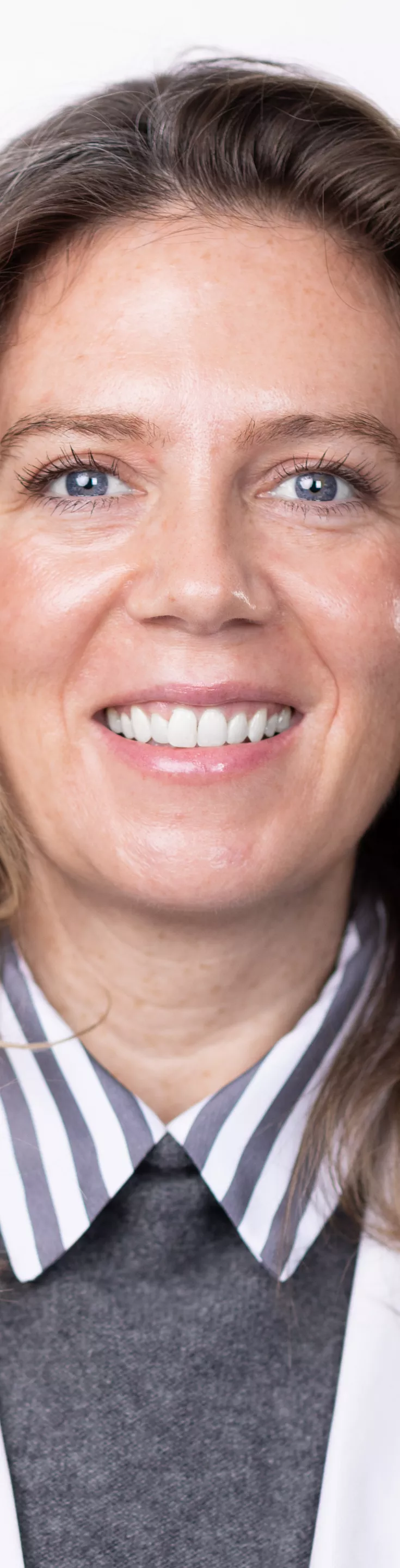 Headshot of Cassie Connerty. She is wearing a blue and white striped blouse, a fuzzy gray sweater, and a white coat.